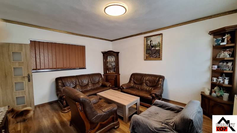 Nappali családi házban bőr ülőgarnitúrákkal és fa mintázatú padlóval.