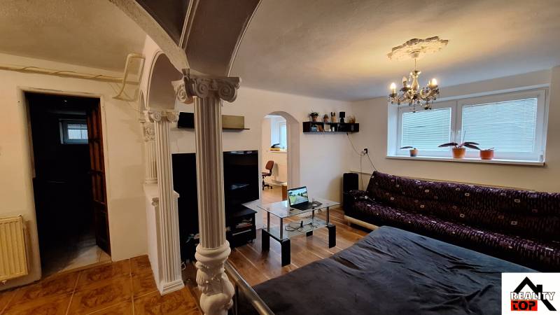 Nappali egy családi házban kanapéval, üvegasztallal és oszlopokkal.