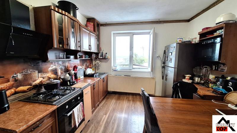 Családi ház konyhája konyhabútorral, háztartási gépekkel és fa dekorációjú padlóval.