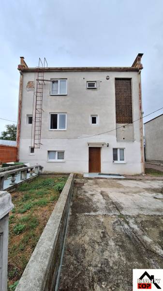 Családi ház Zacharócon egyszerű homlokzattal, ablakokkal és külső lépcsővel.