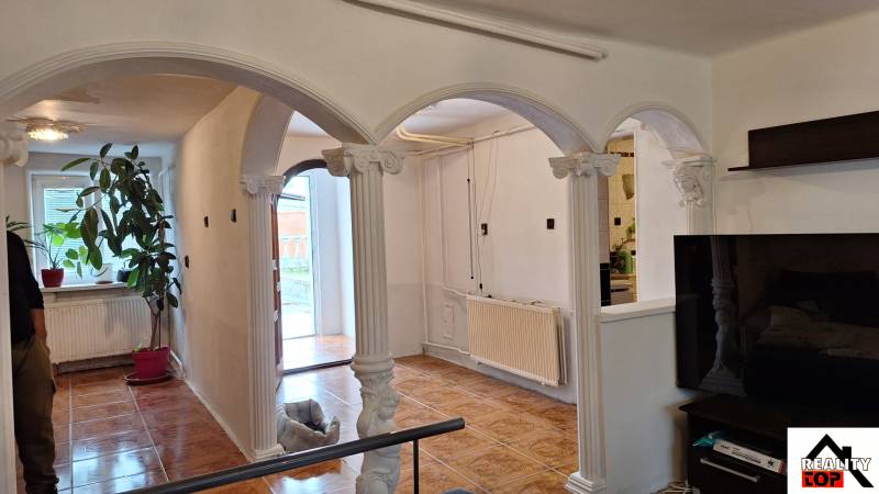 Családi ház belső tere íves oszlopokkal és fa dekorációjú padlóval.