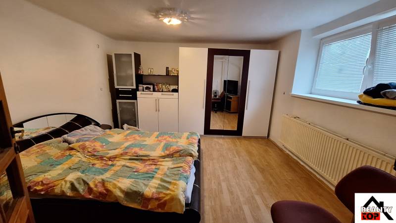 Hálószoba ággyal, szekrénnyel és fa dekorációjú padlóval egy családi házban.