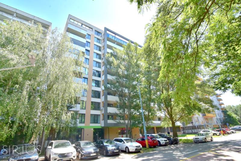 Egy lakóház az Antolska utcában, Pozsony-Petržalkán, zöldövezettel és parkoló autókkal körülvéve.