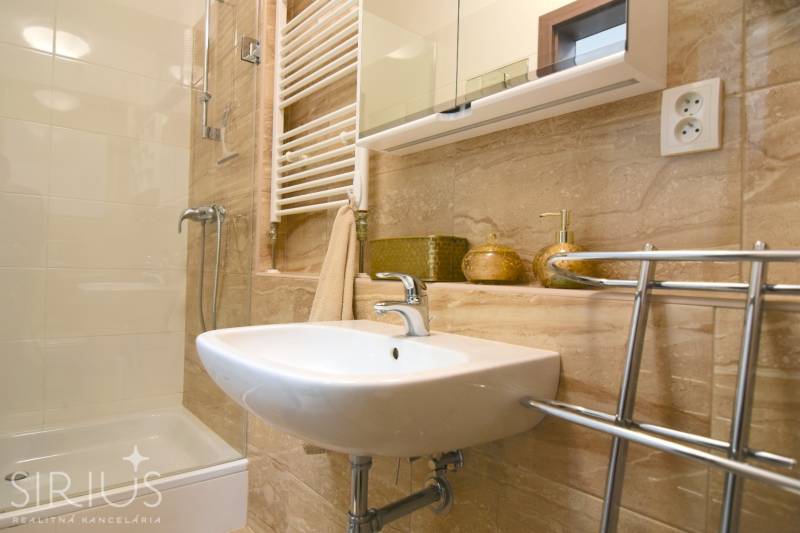 Fürdőszoba mosdóval, zuhanyzóval és tükrös szekrénnyel egy kétszobás lakásban.