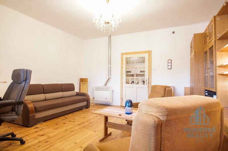 Nappali egy családi házban, fa dekorációjú padlóval, kanapéval és fotelekkel.