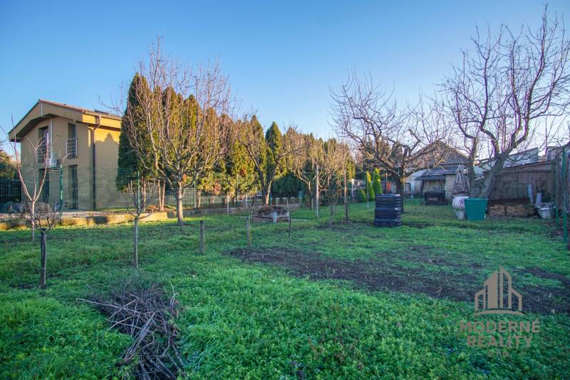 Kert a családi ház mellett a Pod kopcom utcában Érsekújváron, fákkal körülvéve.