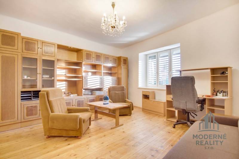 Családi ház belső tere bútorokkal, fa mintázatú padlóval és csillárral.