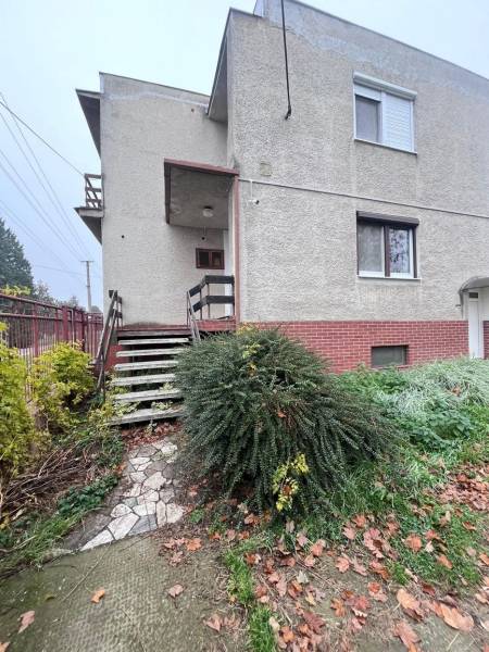 Családi ház Vághosszúfaluban téglából készült lábazattal, lépcsővel és rendezett kerttel.