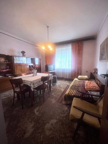 Családi ház belső tere étkezőasztallal, kanapéval és televízióval.