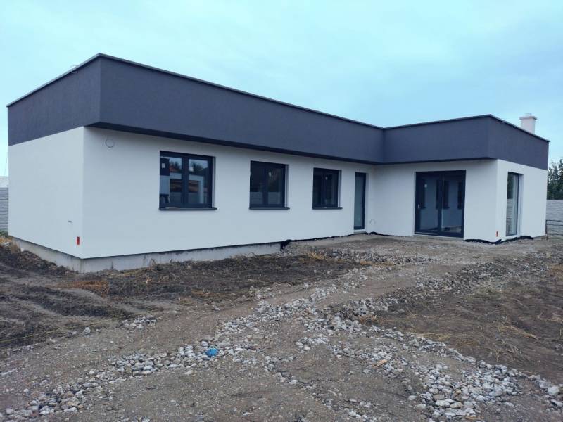 Lapos tetős, világos homlokzatú családi ház Zsigárdon.