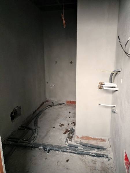 Családi ház belső tere felújítás közben, látható vezetékekkel és befejezetlen falakkal.