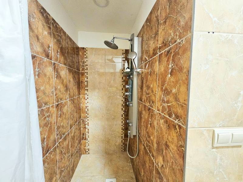 Kerámia burkolatú és zuhanyfüggönyös zuhanykabin a háromszobás lakásban.