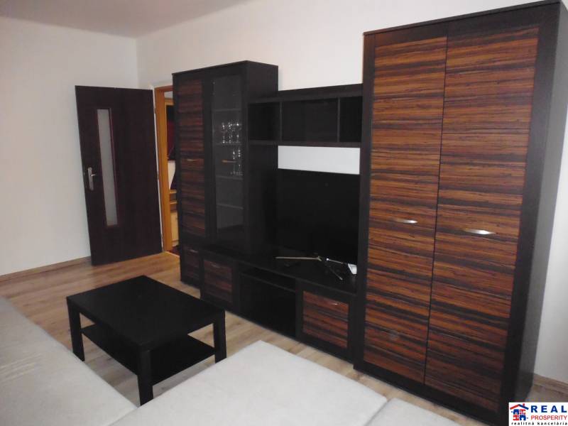 Nappali szoba bútorokkal és fa dekorációjú padlóval egy kétszobás lakásban.