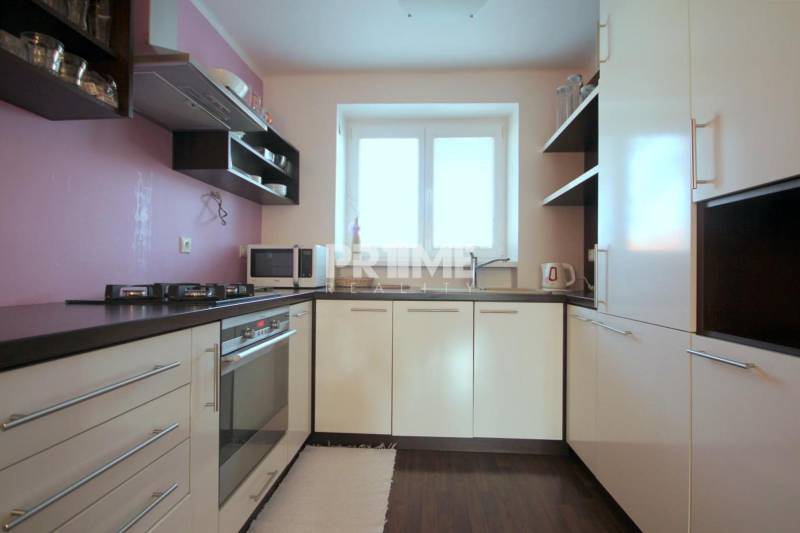 Konyha egy kétszobás lakásban gáz tűzhellyel és fa dekorációjú padlóval.