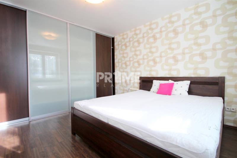 Hálószoba egy kétszobás lakásban ággyal, beépített szekrénnyel és fa dekoros padlóval.