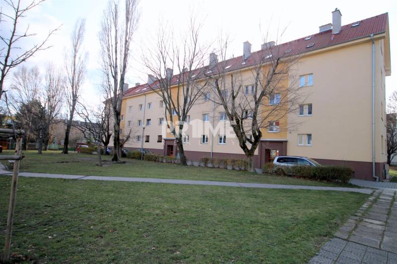 A Kadnárova utcai lakóház Pozsony-Rača városrészében, zöldövezet és járda veszi körül.