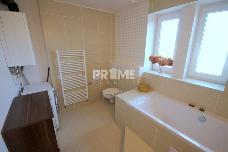 Fürdőszoba káddal, csempével és mosógéppel egy kétszobás lakásban.