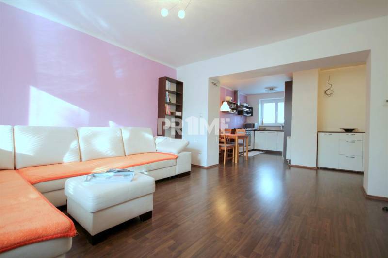 Nappali egy kétszobás lakásban sarokkanapéval és fa dekorációjú padlóval.