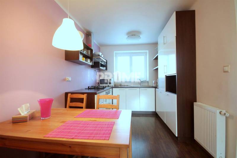 Kétszobás lakás konyhája fa dekoros padlóval és rózsaszín kiegészítőkkel.