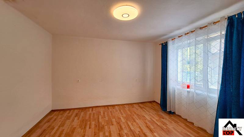 Szoba egy családi házban fa dekoros padlóval és függönyökkel az ablaknál.