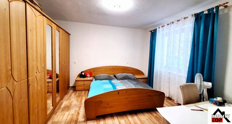 Hálószoba családi házban ággyal, szekrénnyel és fa dekorációjú padlóval.