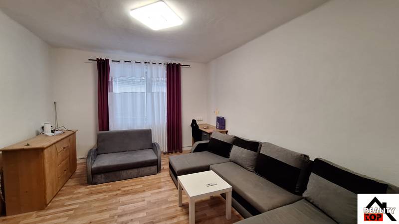 Nappali egy családi házban sarokkanapéval és fa mintázatú padlóval.