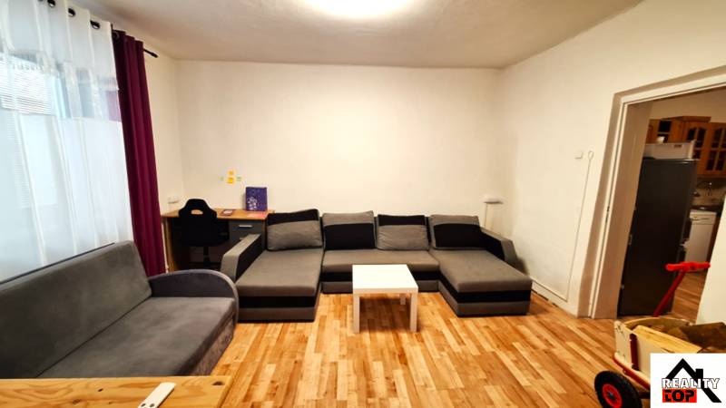 Nappali egy családi házban, fa dekorációjú padlóval és szürke bútorokkal.