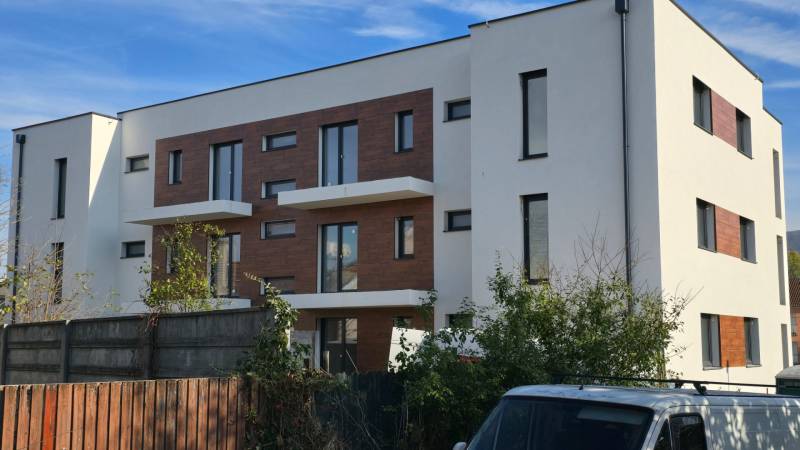 Fehér háromemeletes épület fa dekorációkkal a homlokzaton a Banka utcában, Pöstyénben.