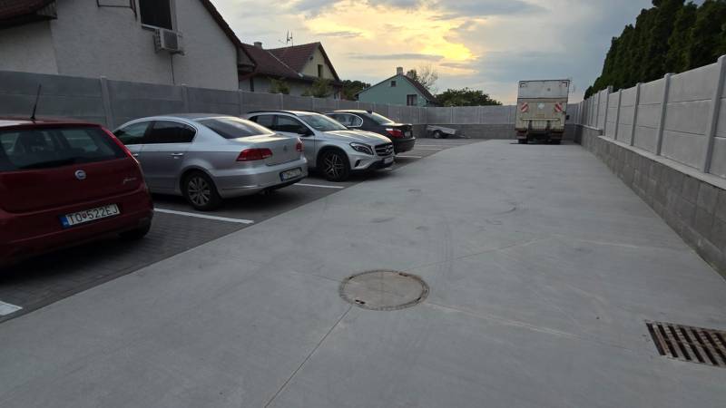 Parkoló a Banka utcában, Pöstyénben, autókkal és teherautóval naplementekor.