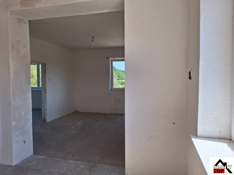 Családi ház belső tere befejezetlen falakkal és betonpadlóval.