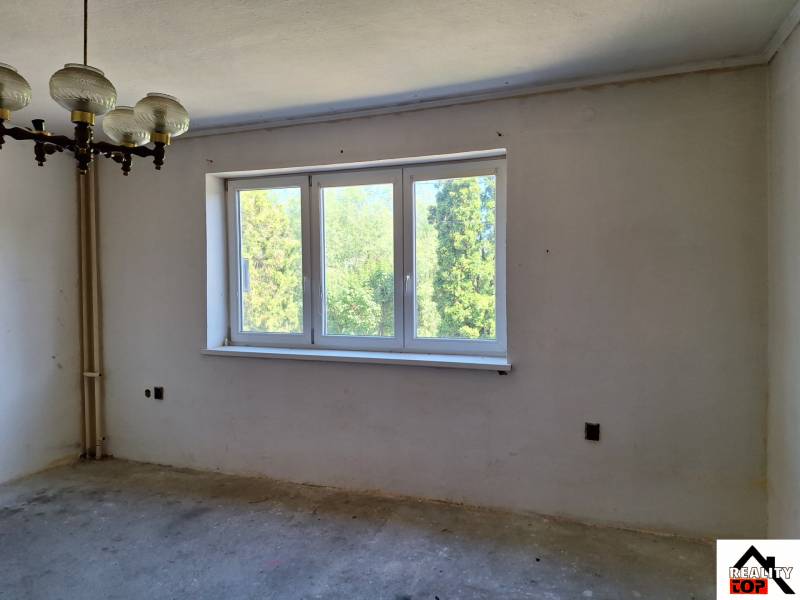 Szoba családi házban nagy ablakkal, eredeti csillárral és kilátással a zöldre.