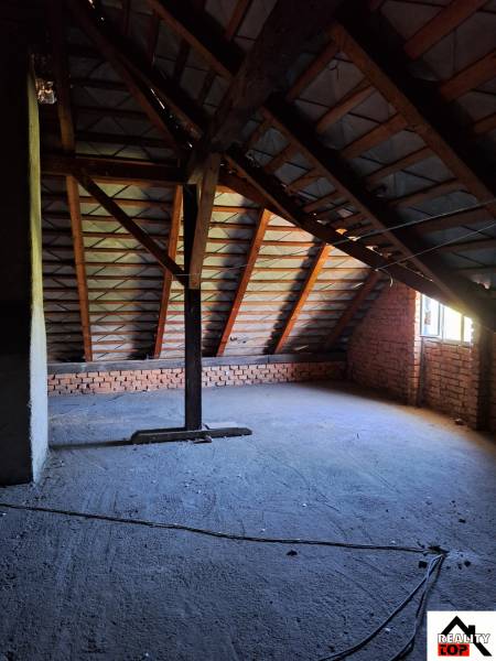 Családi ház tetőtér látszó téglákkal és a tetőszerkezet alatti konstrukcióval.