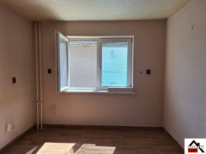 Szoba egy családi házban nyitott ablakkal és fa dekorációjú padlóval.