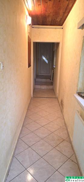 Keskeny beltéri folyosó csempével és fa mennyezettel egy családi házban.