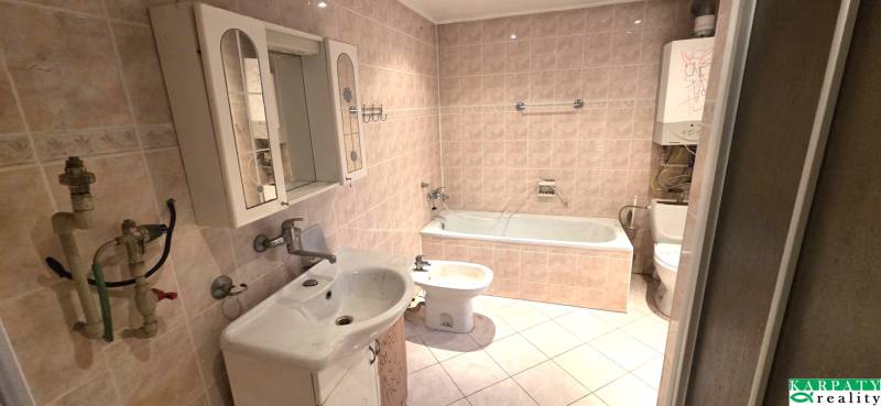 Fürdőszoba káddal, mosdóval és tükrös szekrénnyel családi házban.