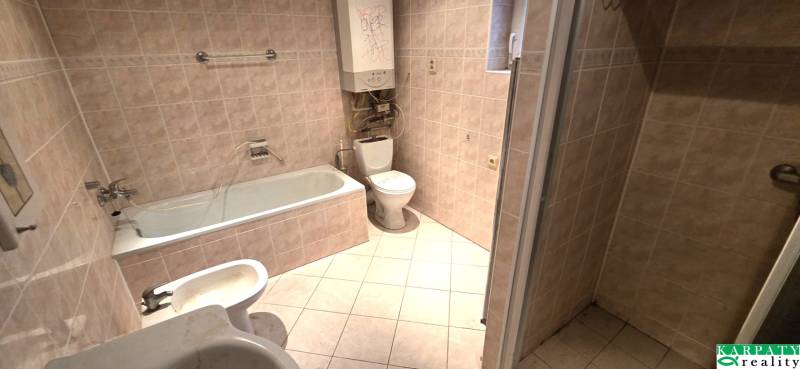 Fürdőszoba családi házban káddal, mosdóval és WC-vel. Világos színű csempék.