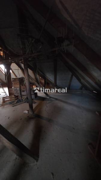 Családi ház padlástere fa gerendákkal és tárolt ládákkal.