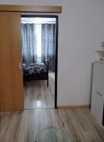 Belső tér fa dekor padlóval, posuvnými dvermi a čiernobielymi závesmi v 3-izbovom byte.