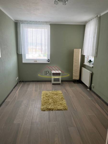 Szoba egy 4 szobás lakásban, fa dekor padlóval és zöld falakkal.