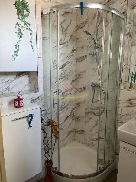 Kompakt fürdőszoba zuhanyzóval és márványburkolattal egy 4 szobás lakásban.