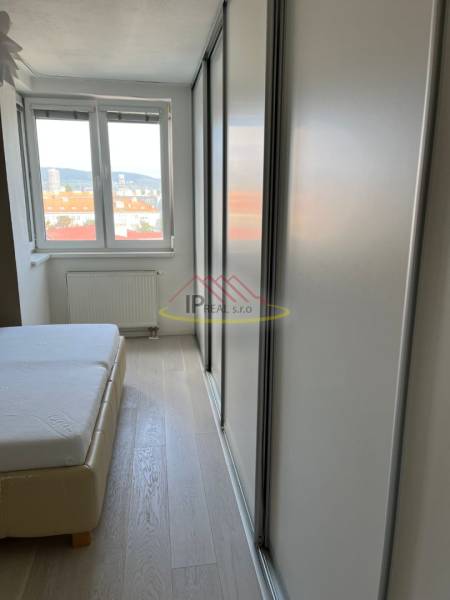 Hálószoba egy 4 szobás lakásban ággyal, fa dekor padlóval és szekrénnyel.