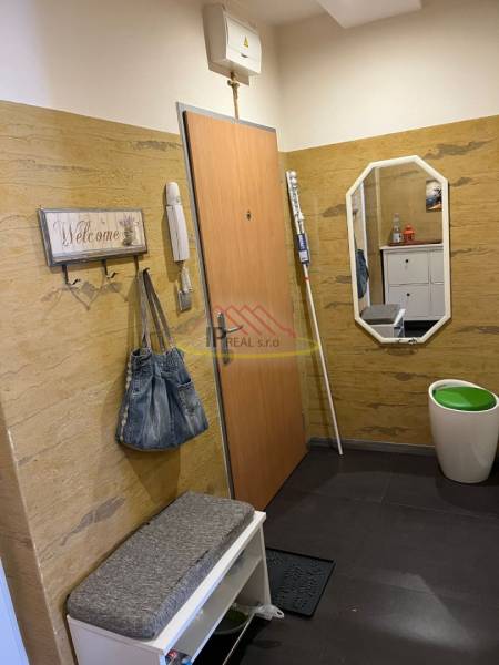 Négy szobás lakás előszobája fogassal, paddal és tükörrel.