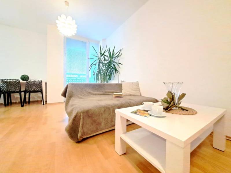 Nappali egy kétszobás lakásban, fa dekor padlóval, kanapéval és asztallal.