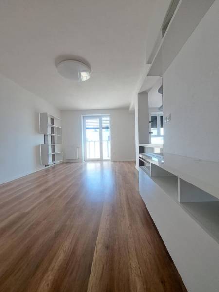 Nappali tér egy kétszobás lakásban, fa dekor padlóval és világos falakkal.