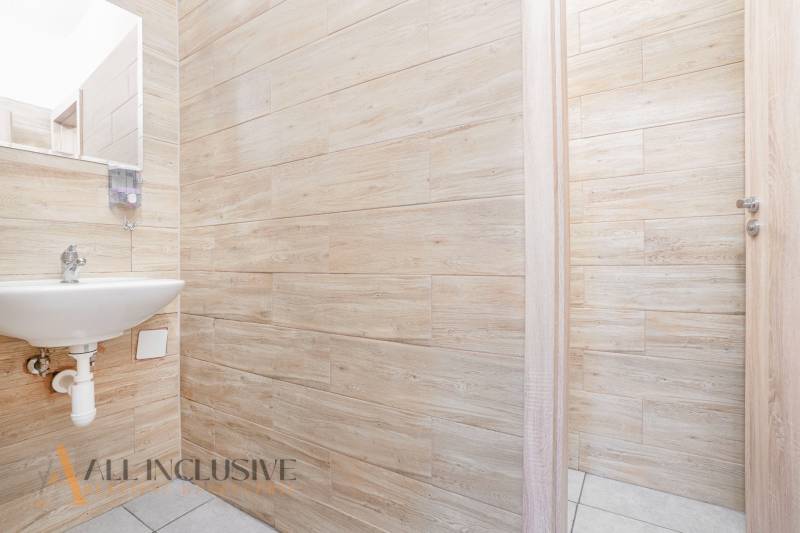 Iroda belső mosdóval, fa falakkal és nyitott ajtókkal.