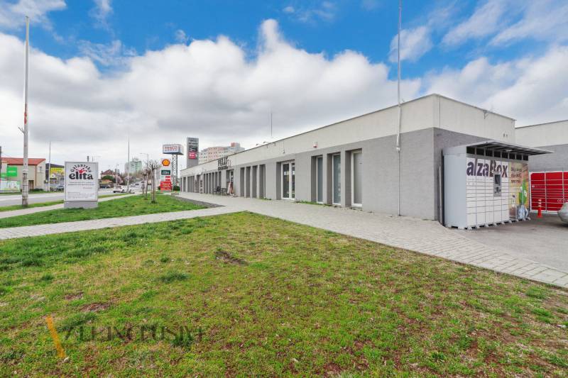 A Vajanského utcán üzlethelyiségek vannak, a járda mellett zöld gyep található.