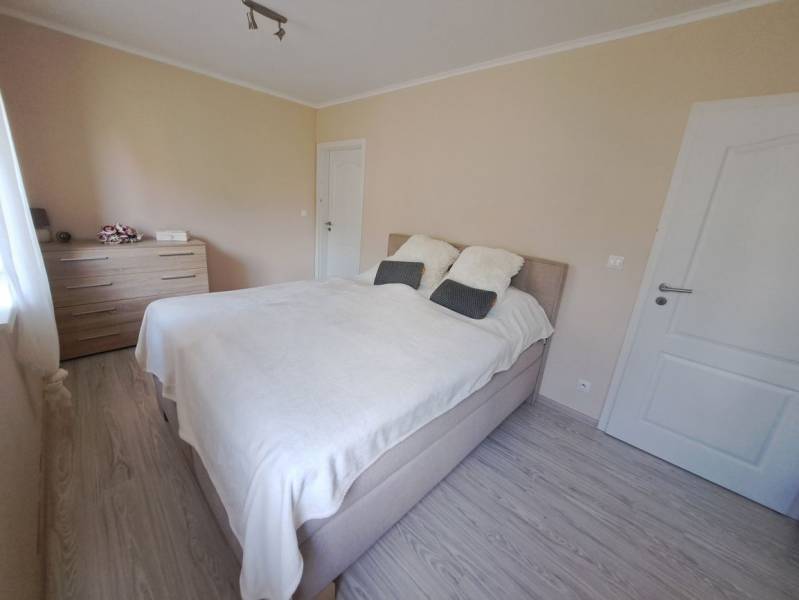 Hálószoba családi házban ággyal, komóddal és fa dekoros padlóval.