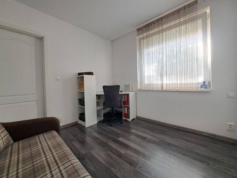 Szoba családi házban, fa dekorációs padlóval, asztallal, székkel és kanapéval.