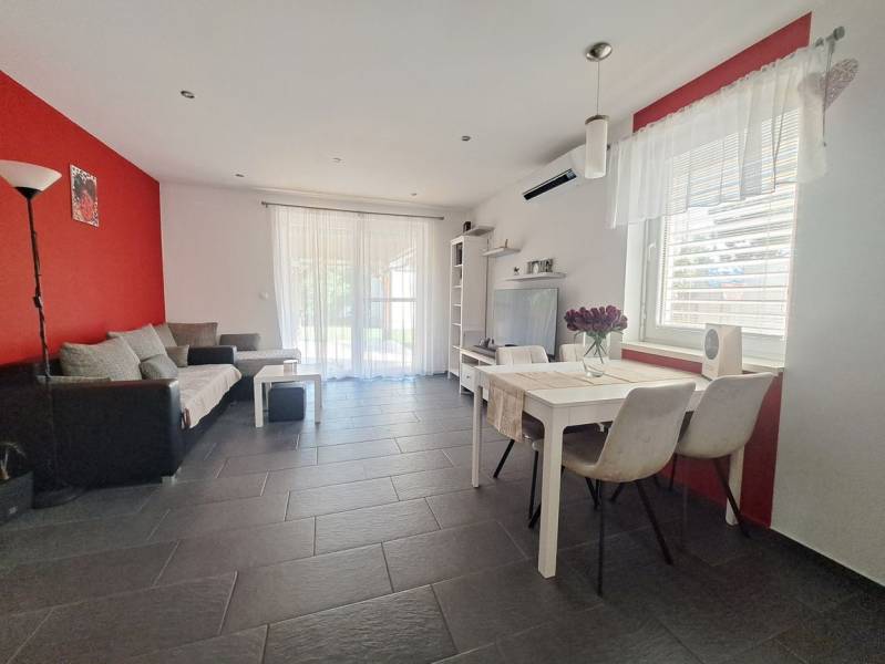 Nappali egy családi házban piros fallal, szürke csempével és fehér bútorokkal.