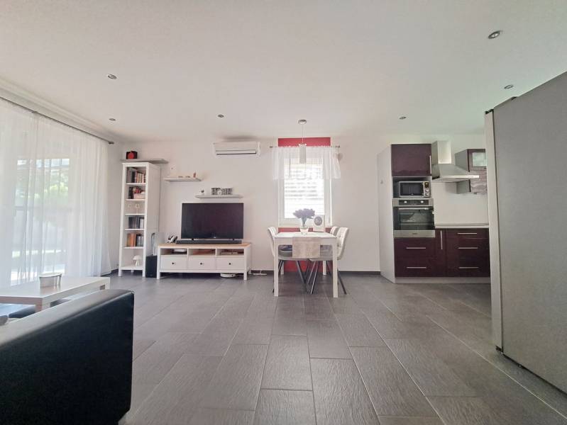 Nappali TV-vel, konyhával és étkezőasztallal, fa dekoros padlóval.